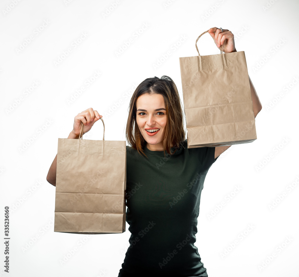 Young woman is holding two grocery shopping bags on white background. Paper bag near face. Isolated 