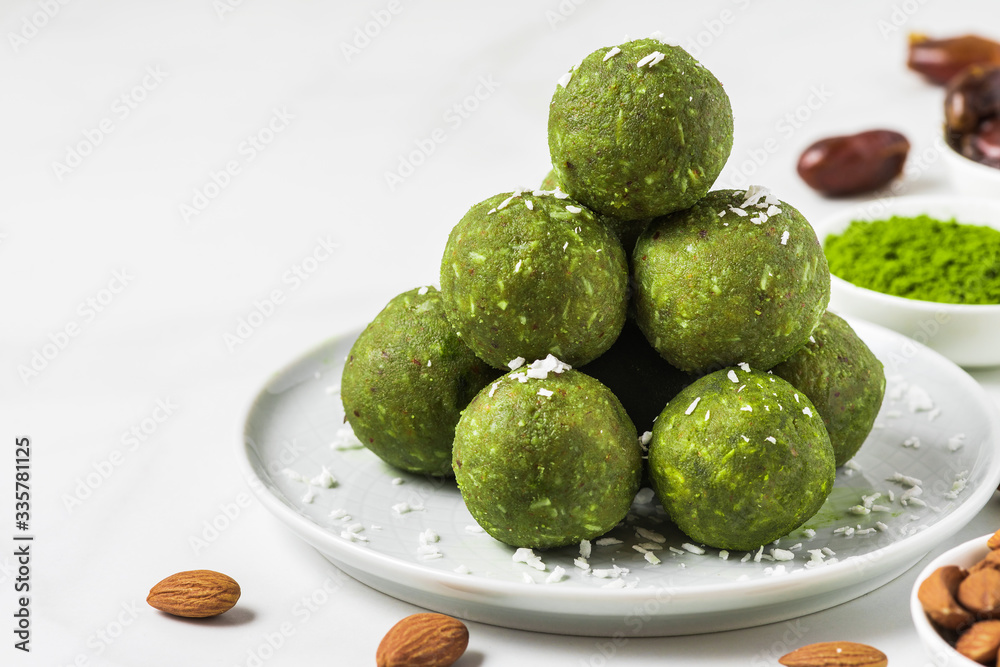 Raw vegan energy balls made of matcha tea, dates and nuts on white background. Healthy vegan dessert