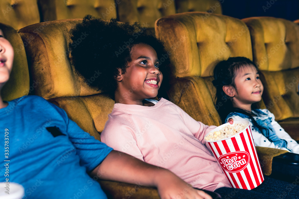 三个孩子在电影院看电影，玩得很开心