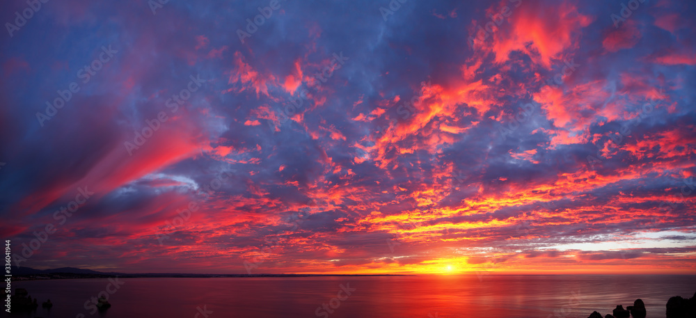 美丽的红色云层和深蓝色和紫色的海洋上令人惊叹的全景日出