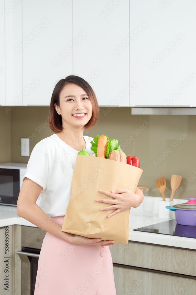 快乐的年轻家庭主妇，带着装满蔬菜的购物袋