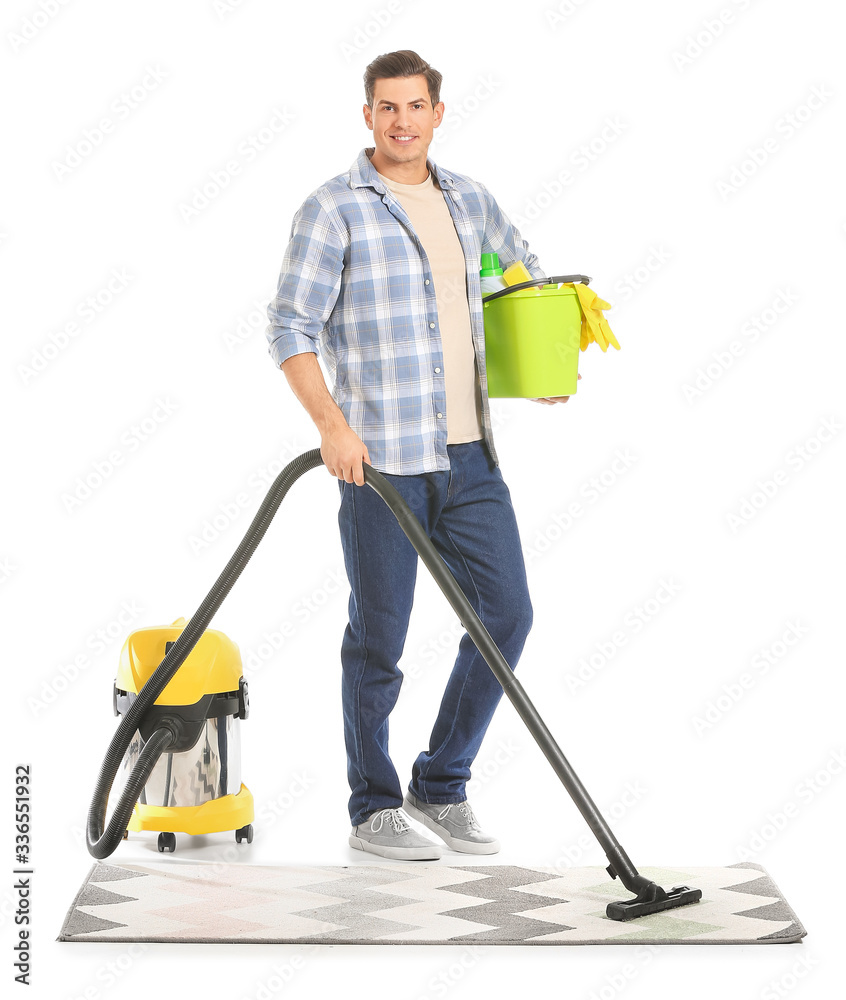 Young man hoovering carpet against white background