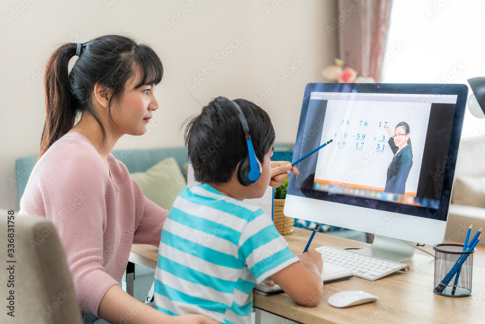 亚洲男生与母亲在客厅的电脑上进行视频会议电子学习