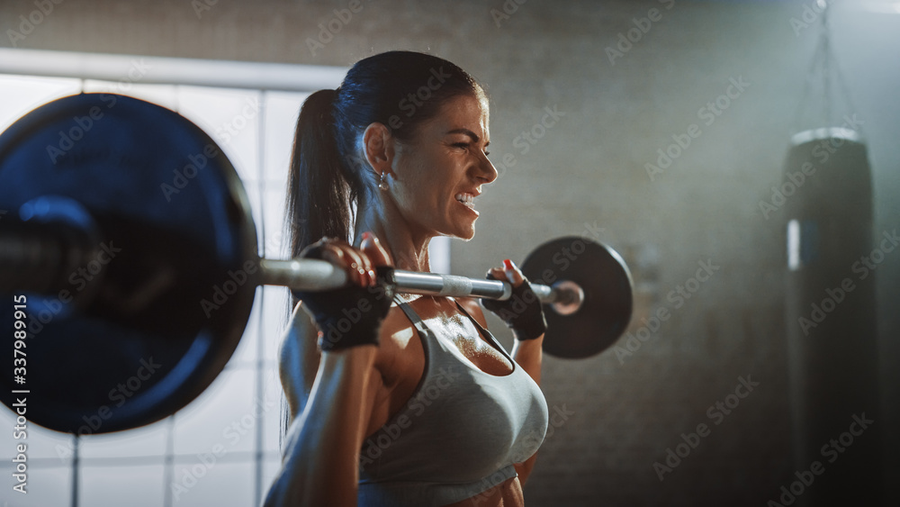 运动美女在健身房用杠铃做高空举重。华丽的女职业选手