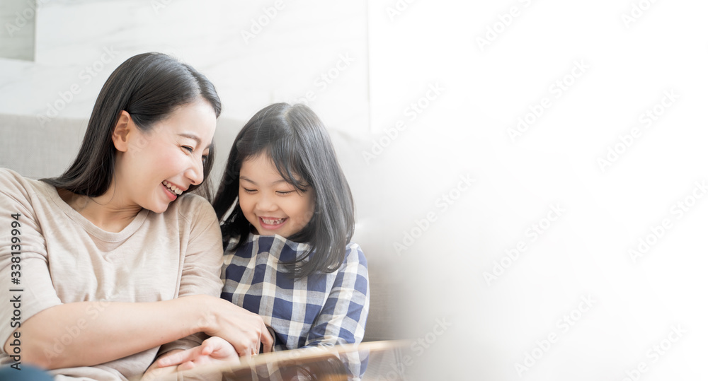 Mother and her daughter child girl playing her mom in sofa living room at home. Happy Asian family c