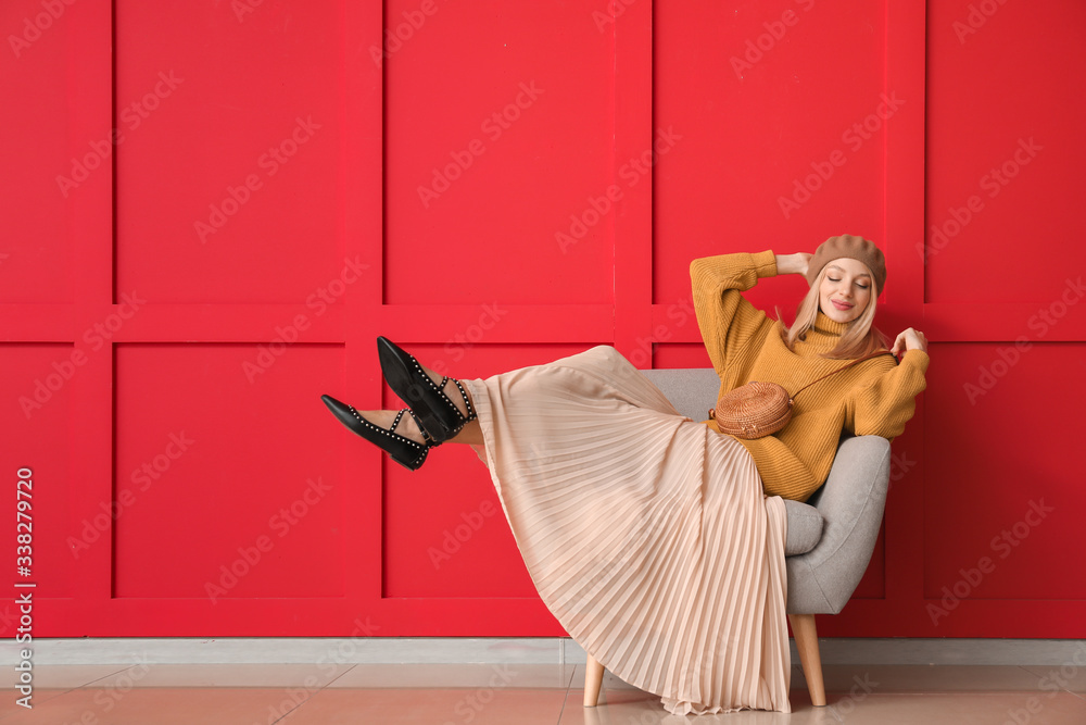 穿着保暖毛衣的年轻女子坐在彩色墙附近