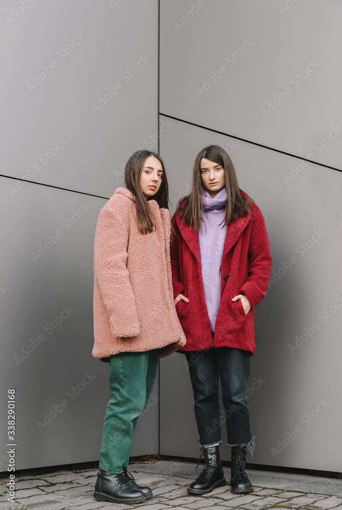 Stylish young women near wall outdoors