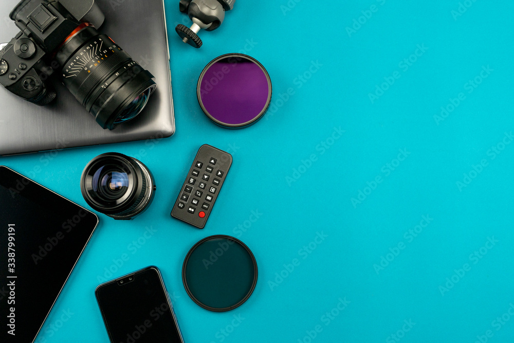 Digital camera with lenses and equipment of the professional photographer on blue background.