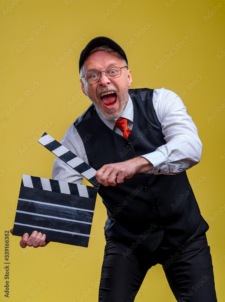 Senior handsome man holding a cinema clapper. Man wearing suit with no jacket. Person isolated again