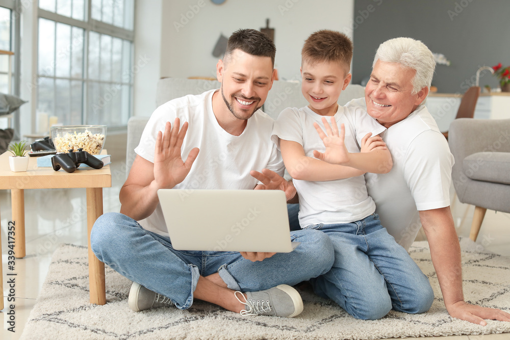 一名男子和他的父亲和儿子在家使用笔记本电脑