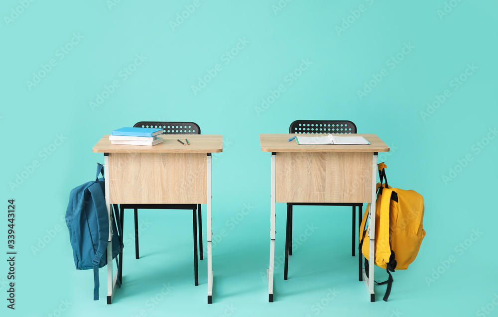 Modern school desks on color background
