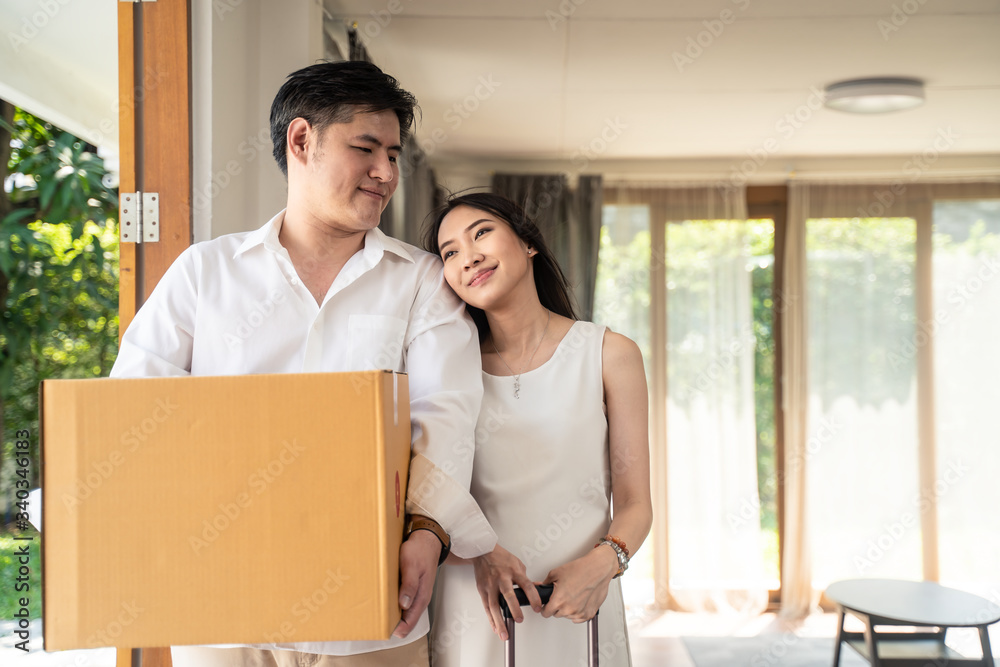 亚洲夫妇搬新房，男子拿着大箱子站在孕妇身边拿着行李