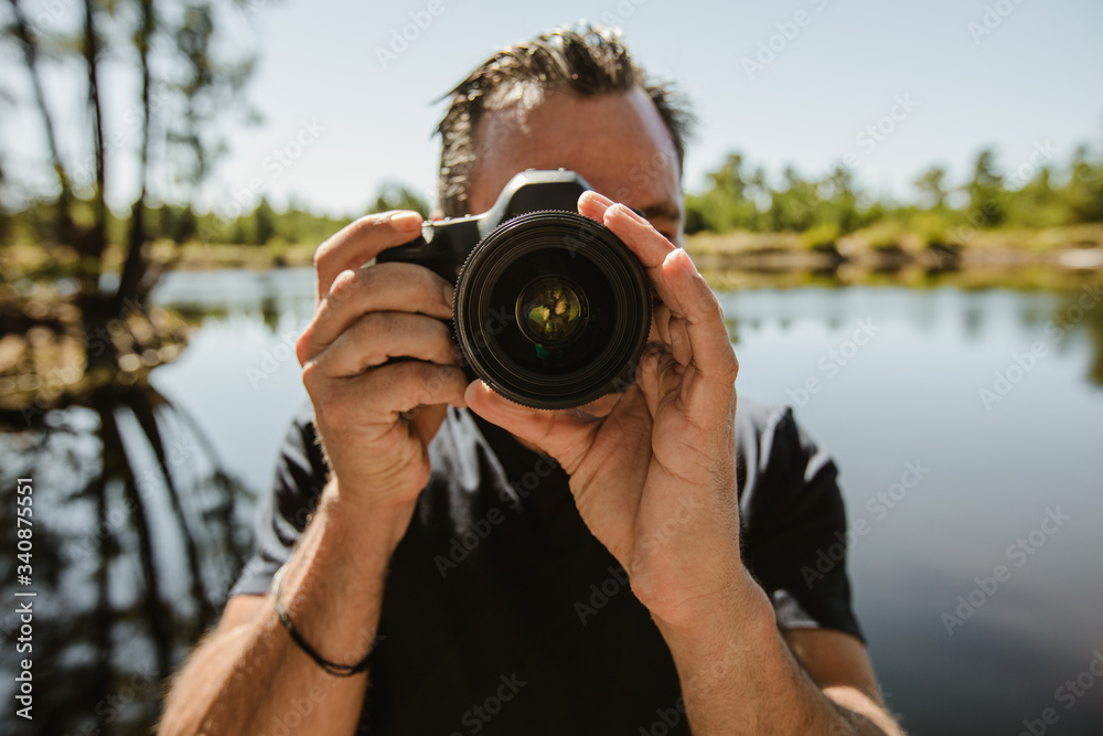 湖边的男摄影师用相机拍照