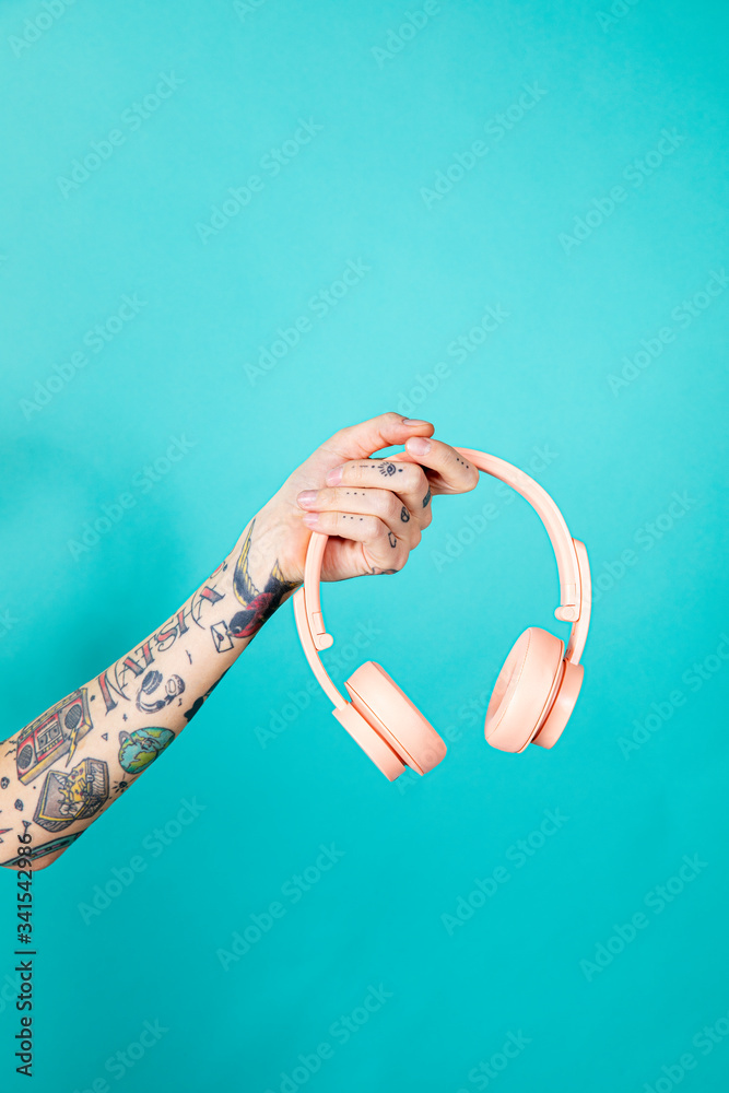 Pink headphones in a tattooed hand
