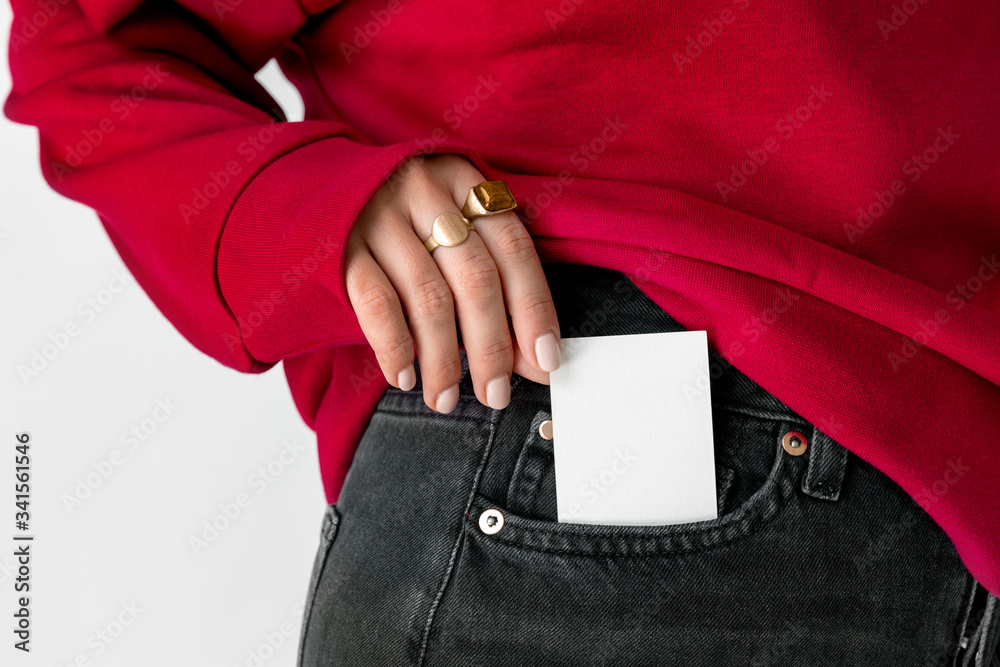 女人把一张白色卡片放在牛仔裤口袋里