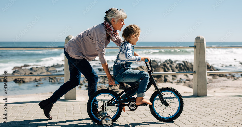 资深女士教一个小女孩骑自行车