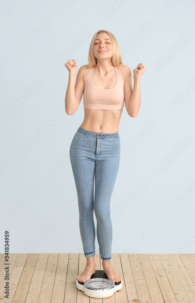 Happy slim woman with scales on color background. Weight loss concept