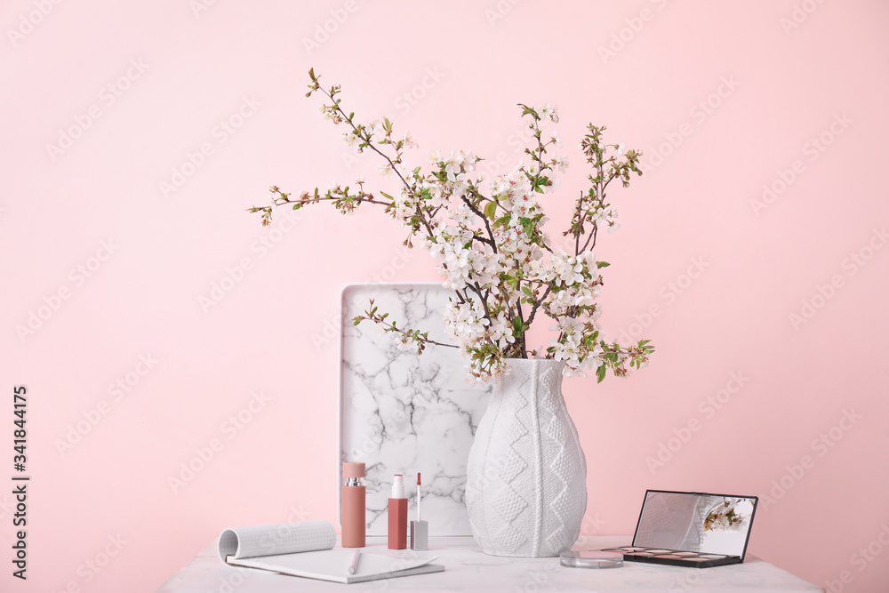 Vase with beautiful blooming branches and cosmetics on table