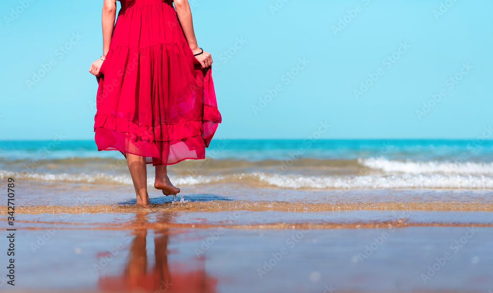 Woman walking by the seaside wearing red dress
