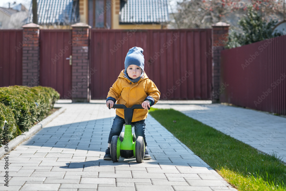 小男孩骑着自行车在他家附近的铺路路上。快乐的童年概念