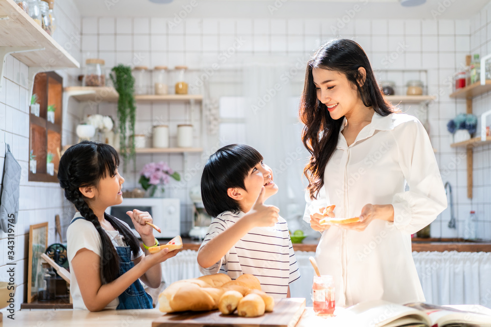 可爱可爱的亚洲家庭在家里的厨房里玩耍、制作食物。微笑的母亲和chi的肖像