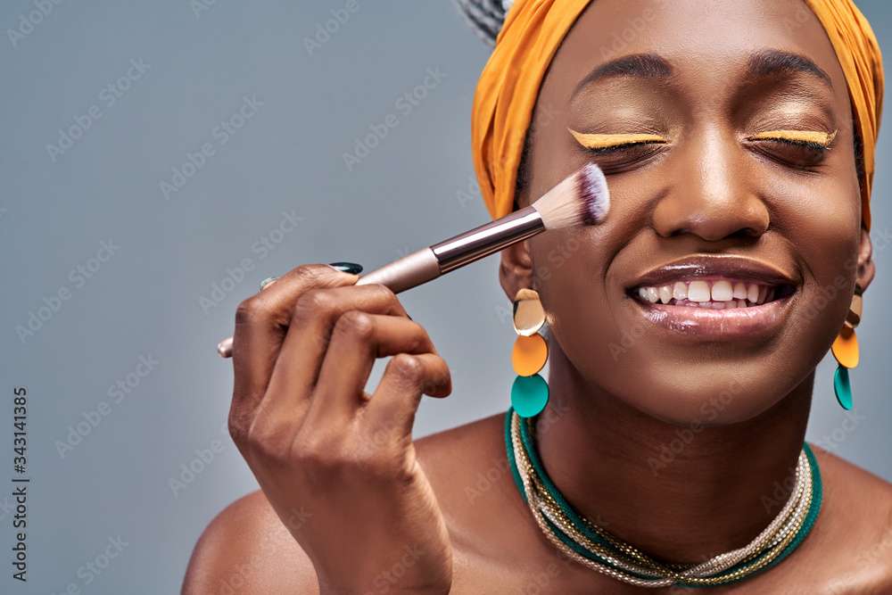 工作室里的年轻非洲女性做身体护理，用刷子化妆、化妆粉和胭脂