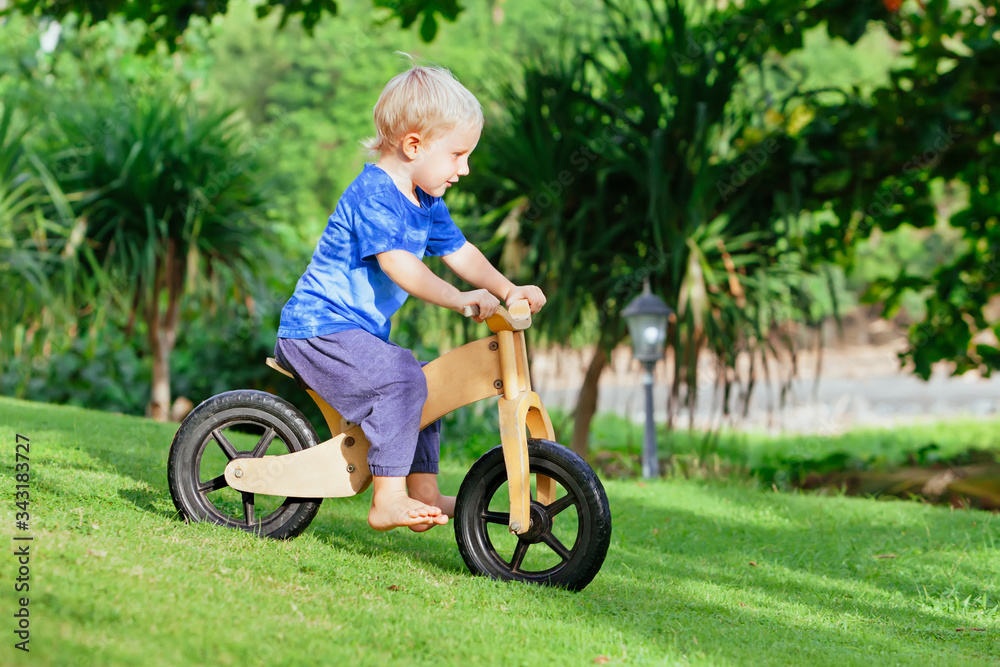 2-3岁快乐的男孩骑着木平衡自行车（跑步自行车）。快乐的赤脚孩子学习whe