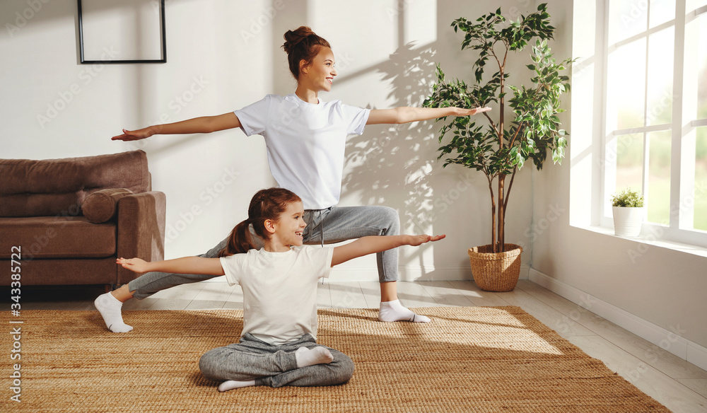 Mother and daughter practicing yoga at home.