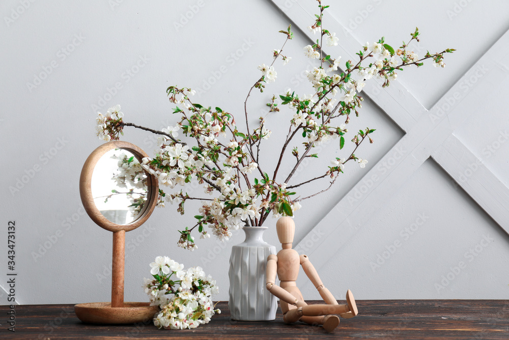 花瓶上有美丽的盛开的树枝、镜子和木制人形