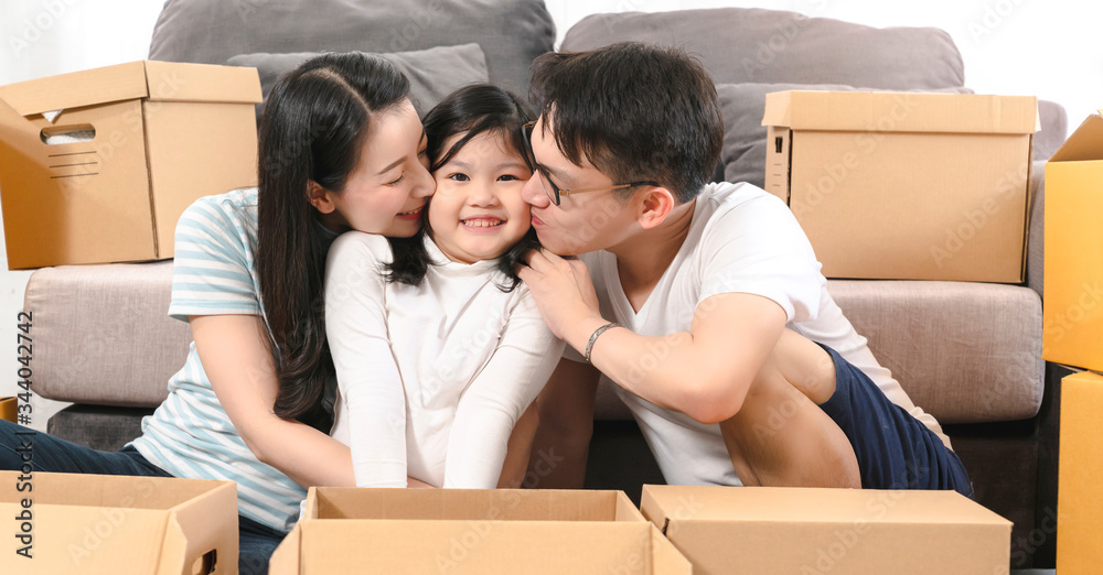 亚洲幸福家庭在新家打开东西时一起微笑和亲吻女儿