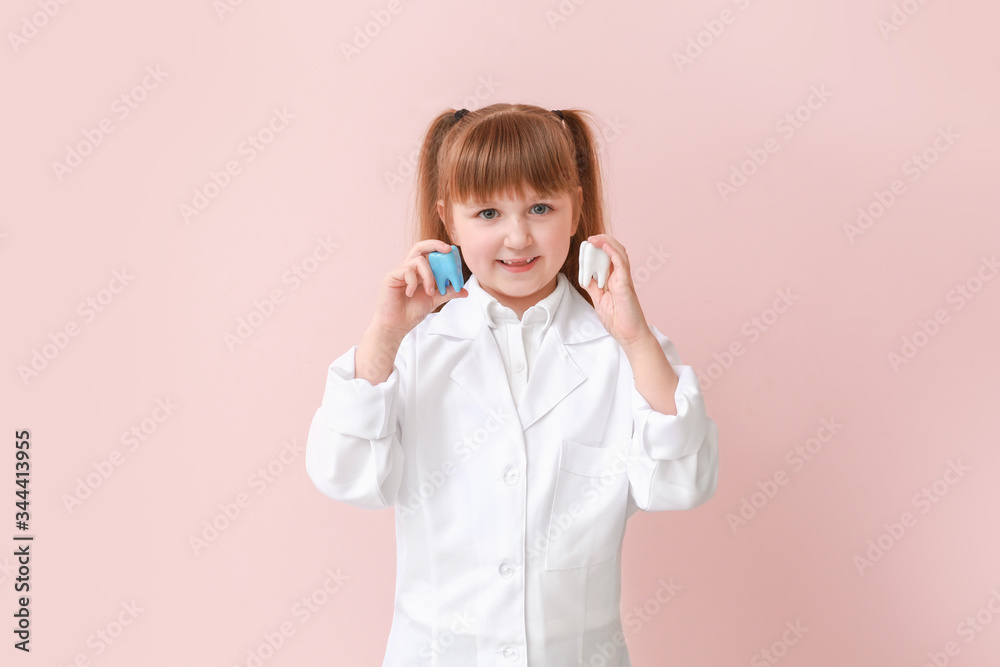 Little dentist with plastic teeth models on color background