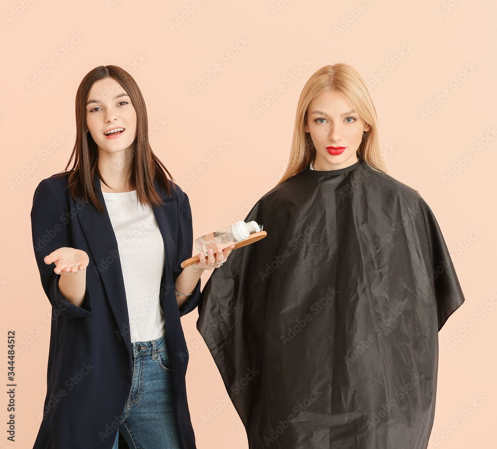 Young hairdresser working with client against color background