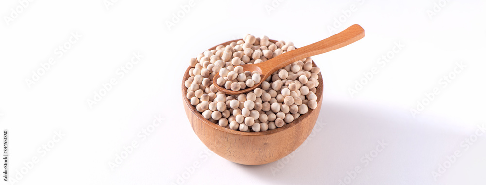 用勺子将生的棕色木薯珍珠放在一个木碗中，用勺子隔离在白色背景上，特写，ing