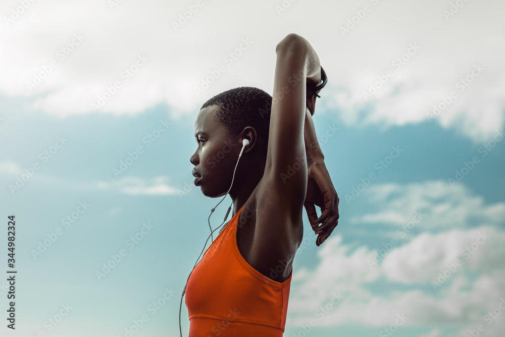 African woman with earphones doing stretching exercise
