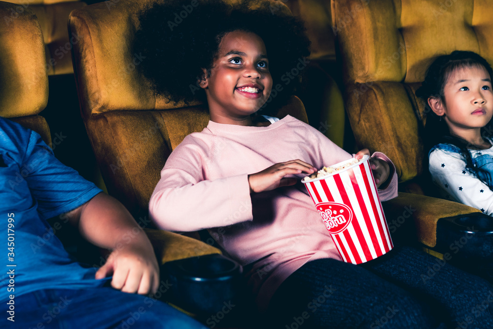 三个孩子在电影院玩得很开心，喜欢看电影