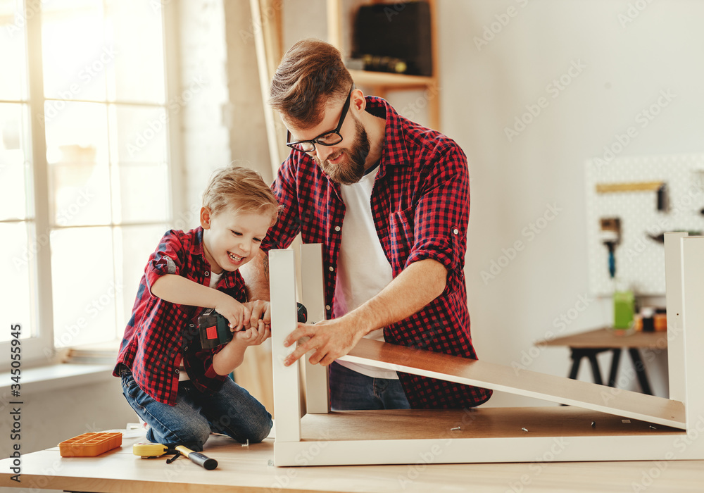 Happy father and son assembling furniture on table.