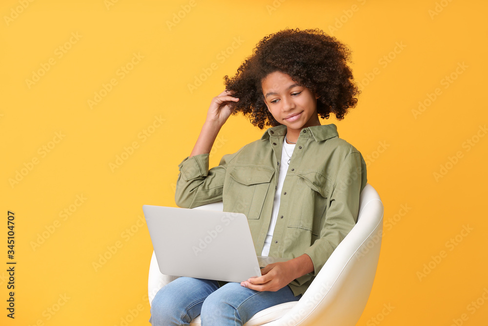African-American teenage blogger with laptop on color background