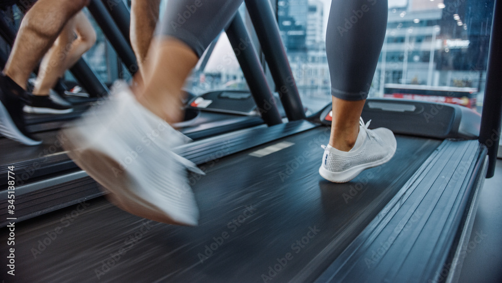 运动人士在跑步机上跑步，做健身运动。强壮的女性和男性在健身房训练