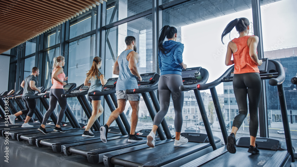 一群运动人群在跑步机上跑步，做健身运动。运动型和肌肉型女性