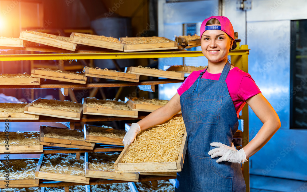 Pasta factory. Production of pasta. Krafted macaroni. Worker with wooden box with pasta.