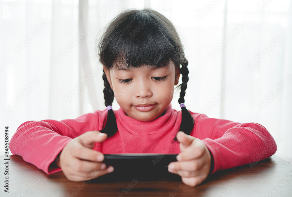 Cute asian child girl playing a smart phone, Smart phone has a negative impact on your child’s devel