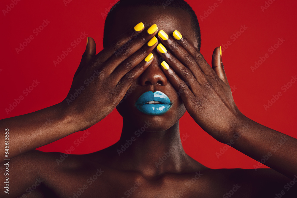 African woman with colorful makeup covering her eyes