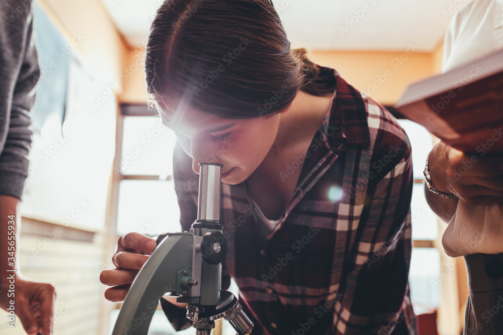 学生在生物课上通过显微镜观看