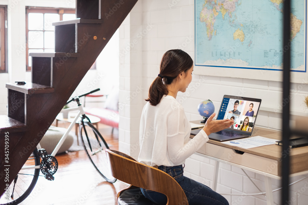 年轻的亚洲女商人在家工作，与同事举行虚拟视频会议