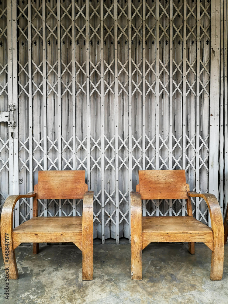 Old wooden chair Waiting for people to sit to relax. With a stretched steel door in the background