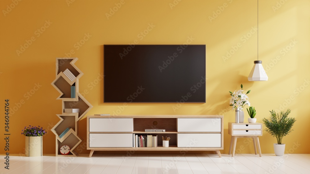 现代客厅橱柜上的电视，黄色墙壁背景上有灯、桌子、花草。