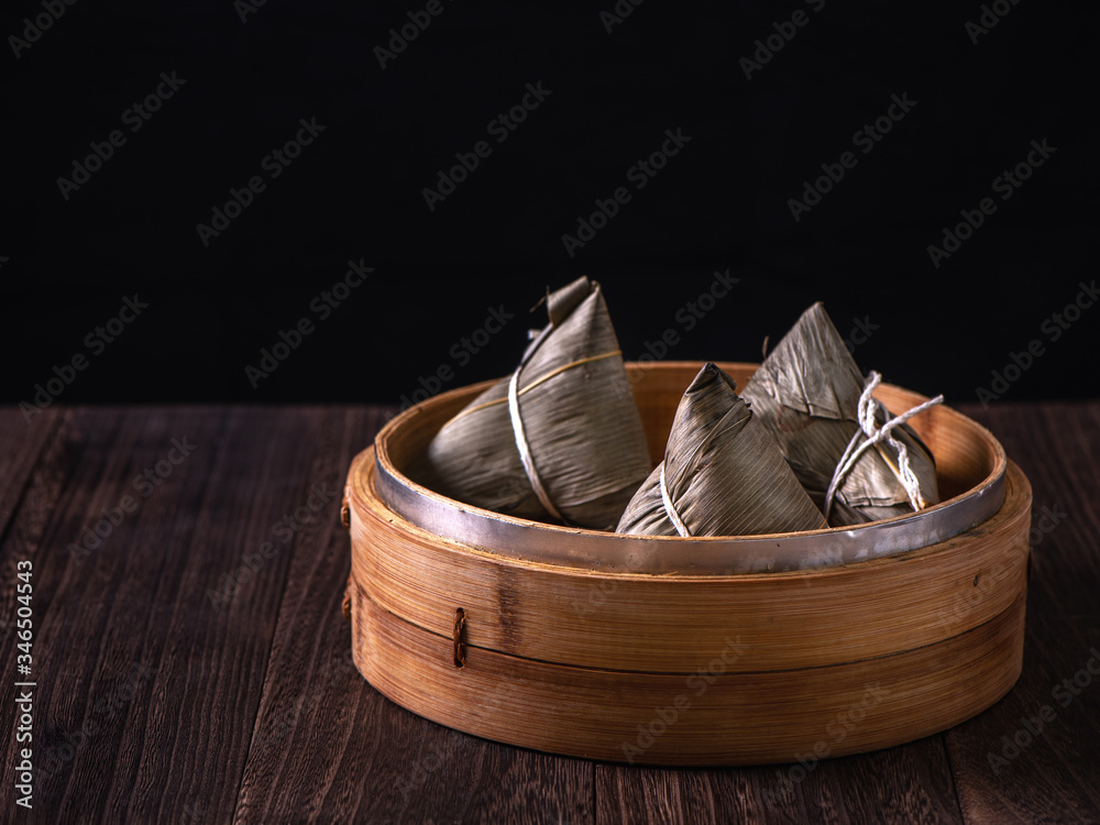 粽子-木桌上蒸笼里的中国粽子，黑色复古背景，代表龙