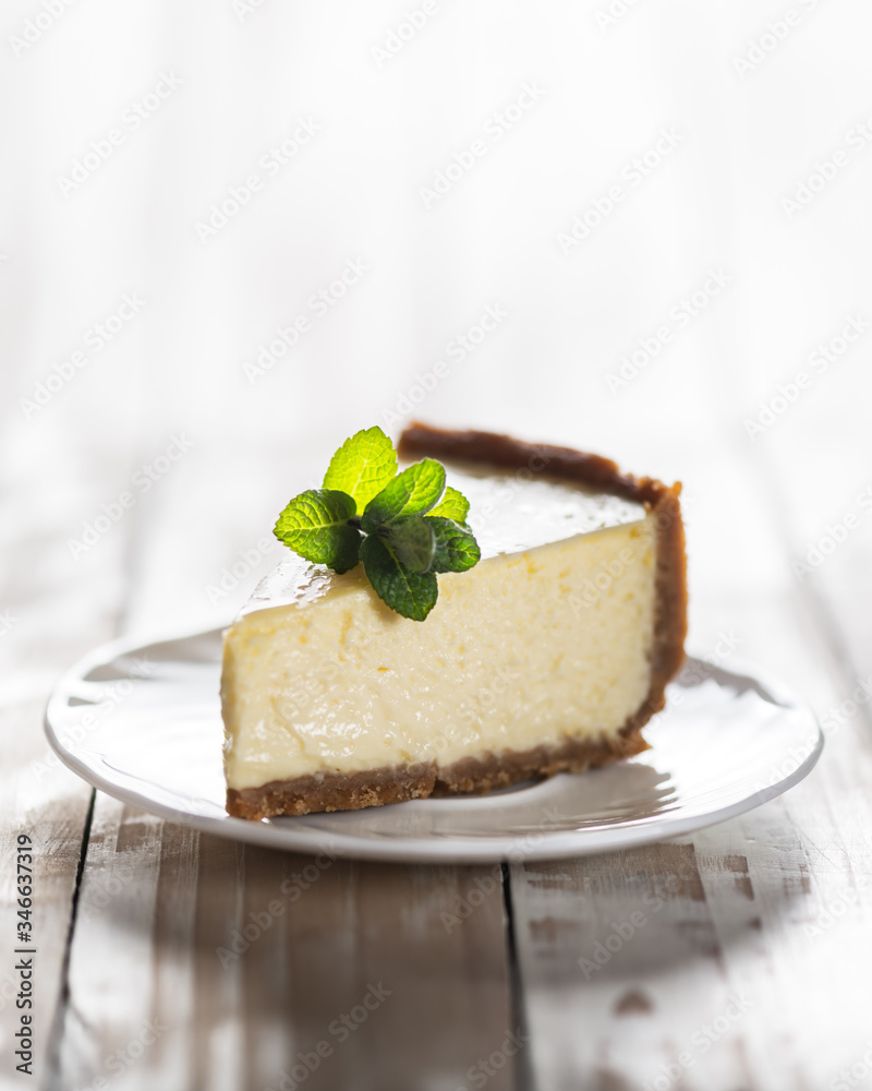 一片经典的纽约芝士蛋糕，在木桌上的盘子里放一枝薄荷。概念