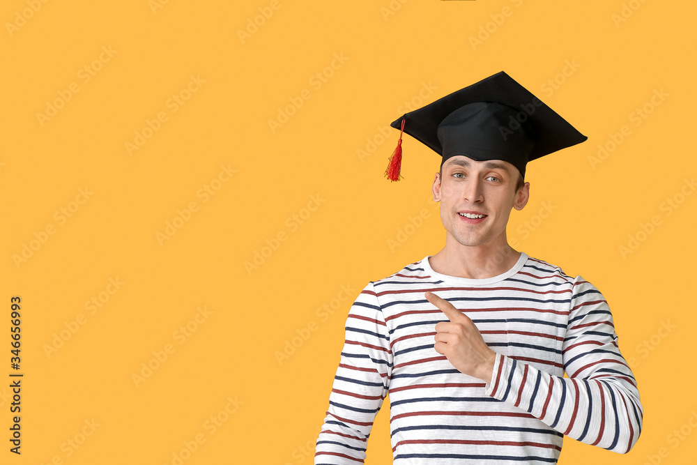 戴毕业帽的年轻人指着彩色背景上的东西