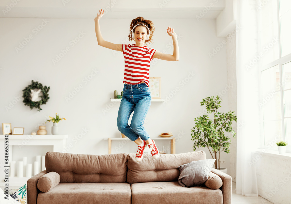 快乐的女人在家里的沙发上听音乐、跳跳舞。
